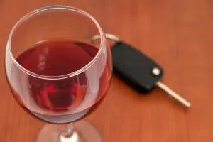 Wine glass with red wine and car key next to it
