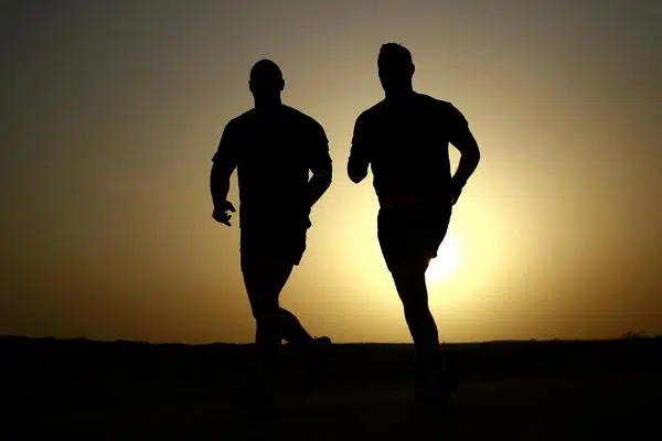 Silhouette of two runners running with the sunrise in the background
