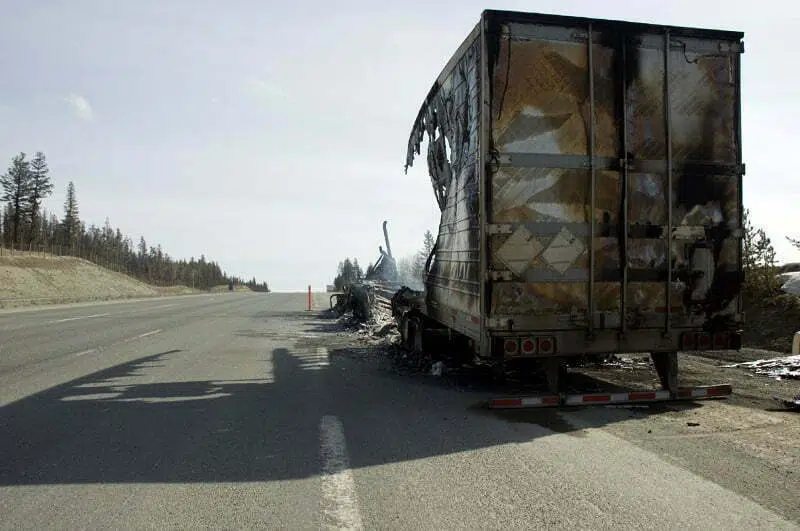 A burnt truck sitting alongside the freeway