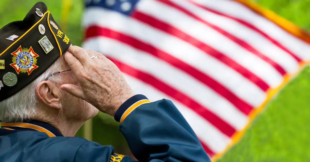 An old white veterans saluting to the USA flag