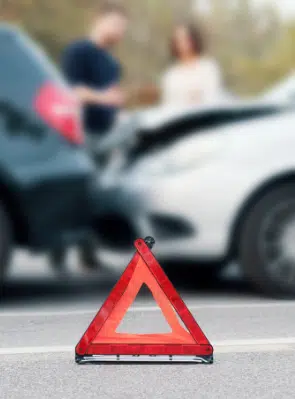 Emergency triangle on the ground with the car accident in the background