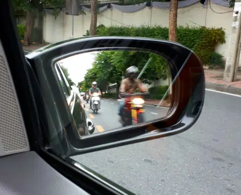 A POV of the right rearview mirror of multiple motorcyclists driving by their car