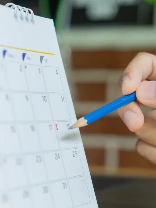 a person marking a calendar with a pencil