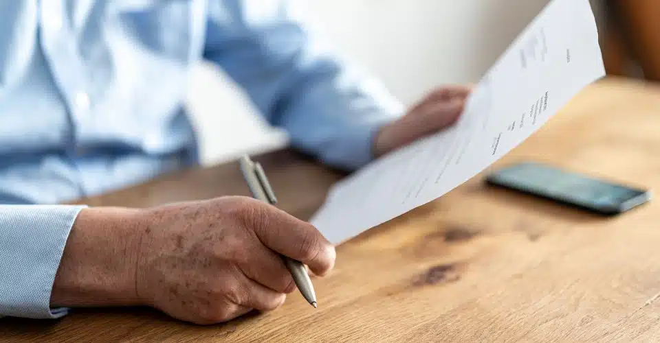 Close-up of a person with a pen in hand and paperwork