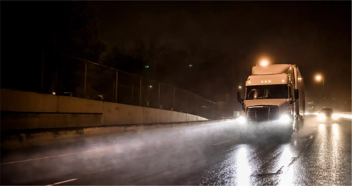 Highway view of a truck driving in rainy and dark conditions
