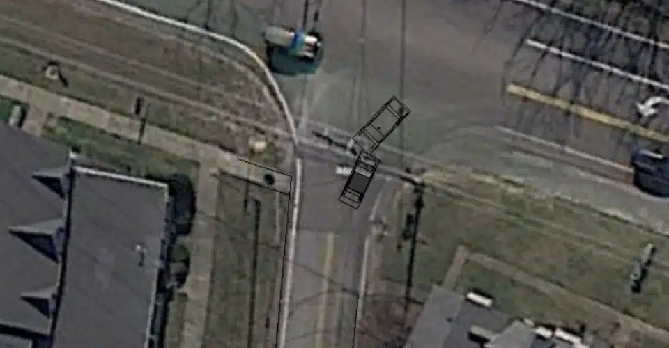 Satellite view of an intersection with two colliding cars drawn in.