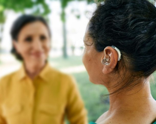 Woman with hearing aid and tinnitus, VA disability benefits for hearing loss.