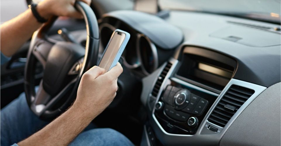 Driver using cell phone while driving, illustrating distracted driving and potential accident causes.