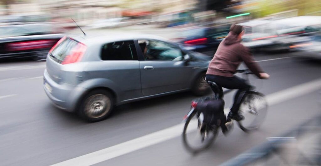 a bicyclist riding alongside traffic on a busy road