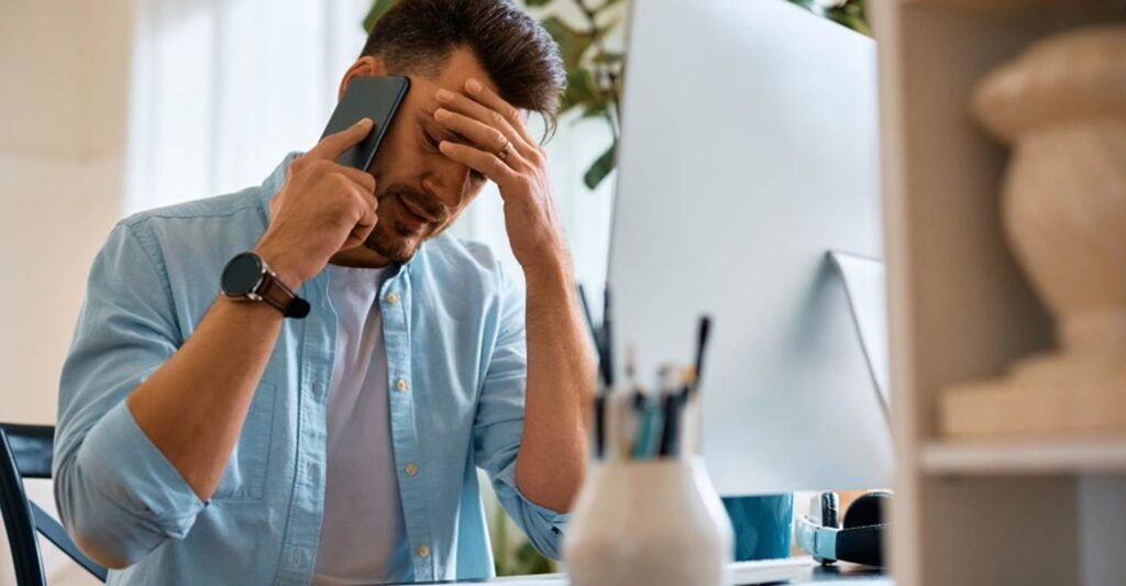 a man at a desk and on the phone looking distressed after a car accident