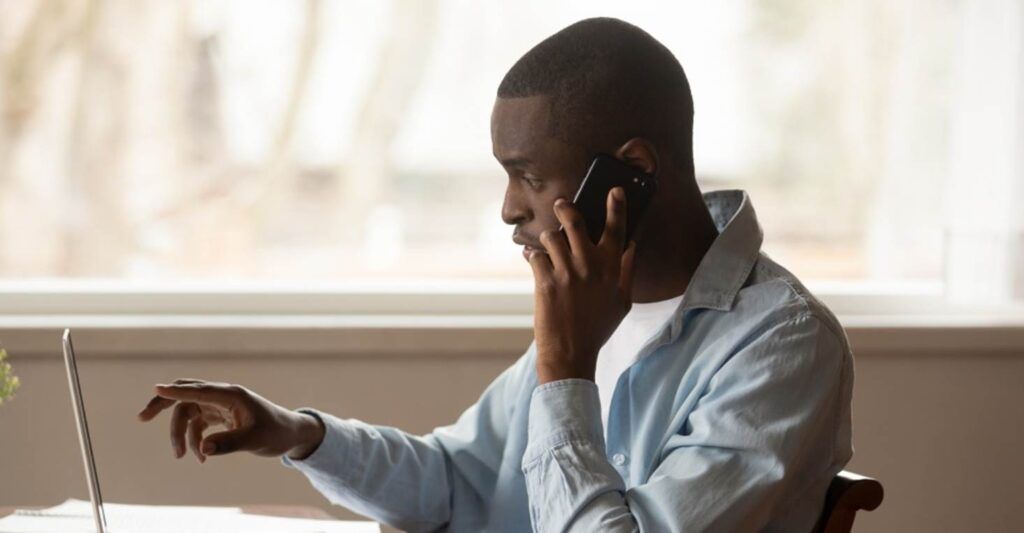 a man on the phone looking at a laptop