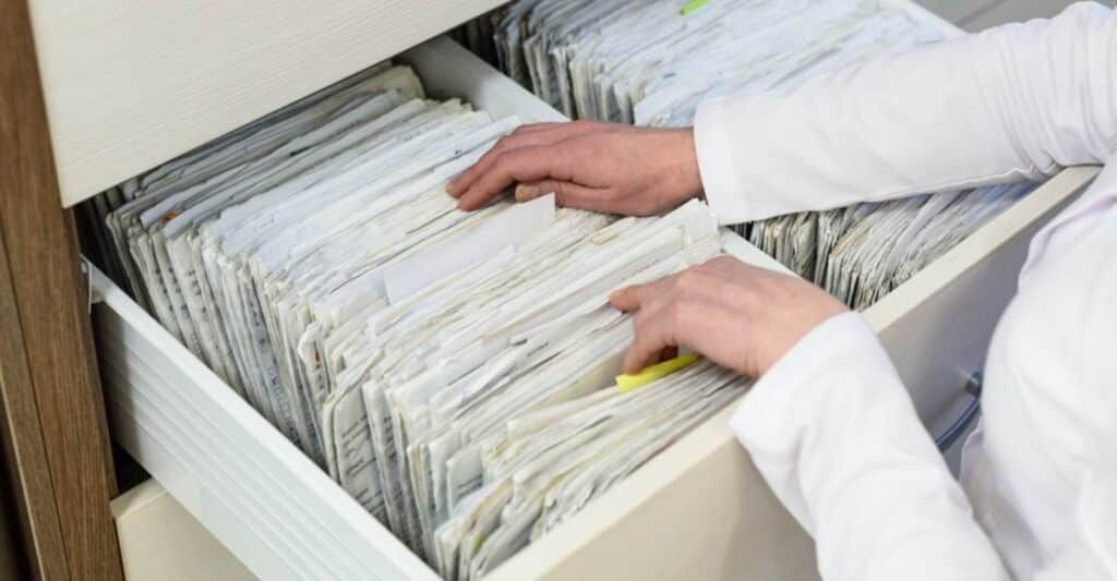 a person going through medical records in a file cabinet